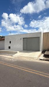 a large white building with a door on the side of a street at Casa baixinha in Ubajara
