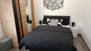 a bedroom with a black bed with two night stands at Studio apartman Relax in Sanski most