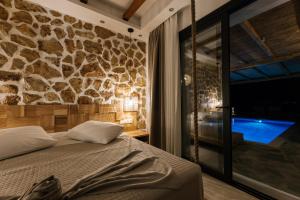 a bedroom with a bed and a stone wall at Naxos Royal Villas in Stelida +11 photos