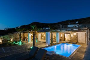 a villa with a swimming pool at night at Naxos Royal Villas in Stelida