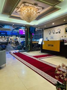 a lobby with a red carpet and a chandelier at Al Muhajir Serviced Apartments Quraish Branch in Jeddah
