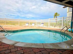 a swimming pool with chairs and a fence at Surfside 15 - Beachtime by Pristine Properties Vacation Rentals in Mexico Beach