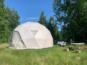 a tent in a field with a table and chairs at Couple Baltic Coast Retreat in Apšuciems