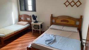 a bedroom with two beds and a table with a lamp at Hotel Gênio in Pouso Alegre