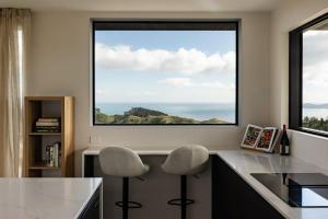 a kitchen with two chairs and a large window at The Hide Kapiti Accommodation in Paraparaumu