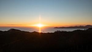a sunset with the sun setting over the ocean at The Hide Kapiti Accommodation in Paraparaumu