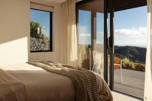 a bedroom with a bed and a large glass window at The Hide Kapiti Accommodation in Paraparaumu