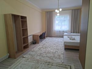 a bedroom with a bed and a desk and a window at Comfort Hotel in Almaty