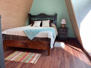 a bedroom with a bed and a wooden floor at Cabaña, fogata, terraza in Santiago Sacatepéquez
