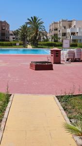 a pool with a red floor and chairs and buildings at Villa lux AP2 in Saïdia