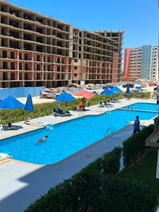 a large swimming pool with blue umbrellas and a hotel at عماره 227 in El Alamein