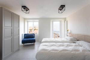 a bedroom with two beds and a blue chair at Antica Villa Branca by Lago Maggiore Rentals in Cannobio