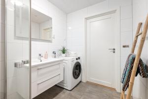 a white bathroom with a washing machine and a sink at Voy Stays Molde sentrum in Molde