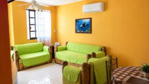 a living room with two green chairs and a table at Villa Bonita Torre 16 in Cozumel