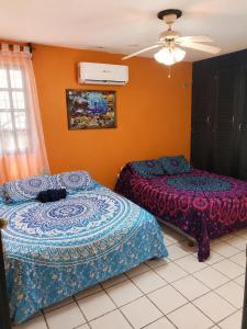 two beds in a room with orange walls at Villa Bonita Torre 16 in Cozumel