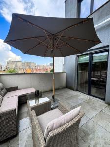 a patio with a table and an umbrella on a balcony at Luxury Apartments C in Braşov