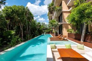 a swimming pool with benches and a house at BT Homes - Tankah Bay Tulum - Exclusivos apartamentos con piscina a metros del mar in Tancah