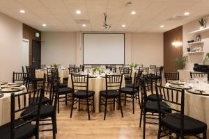 a conference room with tables and chairs and a screen at Kins Hotel in Los Angeles
