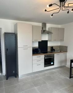 a kitchen with white cabinets and a black refrigerator at Le studio signature in Vedène +8 photos