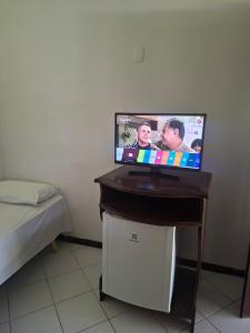 a flat screen tv sitting on a table next to a bed at Girassol praia hotel in Valença +4 photos
