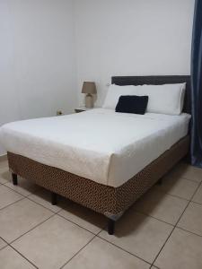 a large bed with white sheets and pillows on it at Apartamentos Trebol in Comayagua