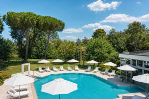 a swimming pool with umbrellas and chairs and a building at Termeterna Resort in Abano Terme