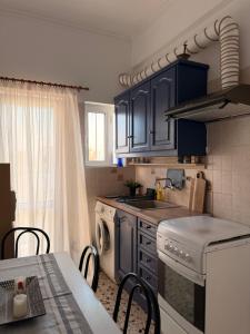 a kitchen with blue cabinets and a sink and a table at KROKOS HOUSE in Aliveri