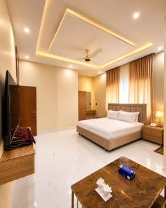 a bedroom with a bed and a tv and a table at Hotel Regent DHA in Karachi