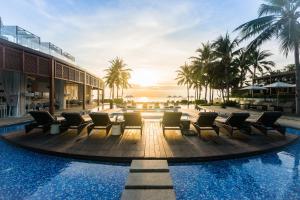 a pool at the resort with chairs and palm trees at InterContinental Hua Hin Resort by IHG in Hua Hin