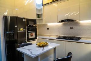 a kitchen with a white table and a black refrigerator at CozyKeys luxurious Apartment in Abuja