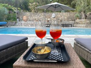 a tray with two glasses of beer and snacks on a table by a pool at Mas Lou Piastoun in Fayence