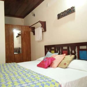a bedroom with a bed with three pillows on it at Krushikoota Homestay in Sringeri
