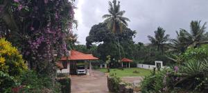 a garden with a pavilion and palm trees and flowers at Krushikoota Homestay in Sringeri