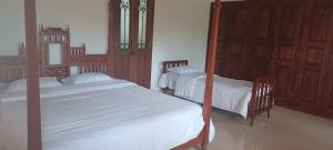 two beds in a bedroom with wooden furniture at Krushikoota Homestay in Sringeri