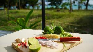 a cutting board with vegetables and a knife on a table at Private Sunset Beachfront Thainee Villa in Nathon Bay