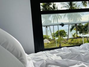 a bed with a view of the ocean from a window at Private Sunset Beachfront Thainee Villa in Nathon Bay