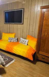 a bedroom with a yellow bed and a flat screen tv at Maison Cavalese - Polar Express in Cavalese