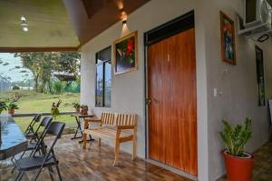 a porch with a table and chairs and a wooden door at Cabinas Los Colibris in Pocosol +16 photos