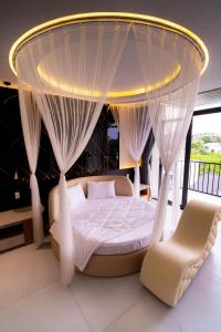 a bedroom with a bed with curtains and a chair at Mia Hotel in Ga Trảng Bôm