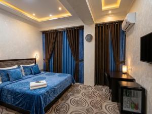 a hotel room with a blue bed and a television at Hotel Buston in Chkalovsk