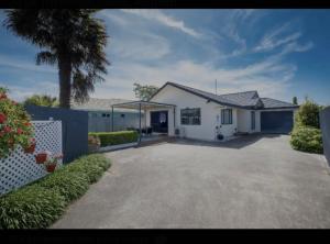 a white house with a palm tree and a driveway at The Napier Stay in Napier
