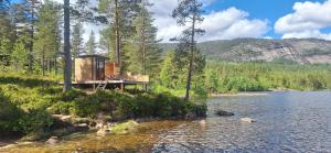 a cabin in the woods next to a body of water at Telemark Camping in Hauggrend