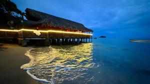a pier with lights on the water at night at La aldea in Capurganá