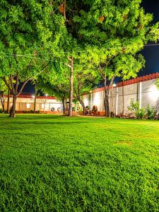 a field of green grass with trees and a building at Mystic Paradise in Jaipur +3 photos