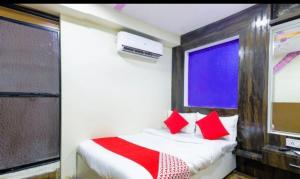 a bedroom with a bed with red pillows and a window at Hotel shree in Indore