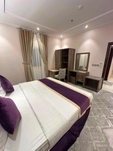 a hotel room with a large bed and a desk at شقق البيلسان الذهبي للشقق المخدومة in Jeddah