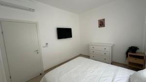 a white bedroom with a bed and a tv on the wall at Private Pool Retreat for Two - Golan in Qasrîne +10 photos