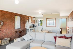 a living room with a couch and a brick wall at Viewpoint in Tathra