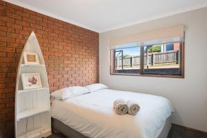 a bedroom with a bed and a brick wall at Viewpoint in Tathra