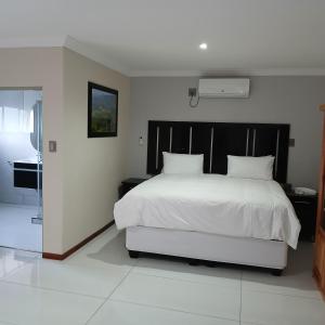 a bedroom with a white bed with a black headboard at RS GARDEN GUESTHOUSE in Thohoyandou